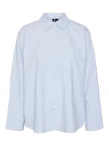 Camisa celeste de corte oversize, con cuello clásico, cierre frontal con botones, bolsillo en el pecho y mangas largas con puños abotonados.