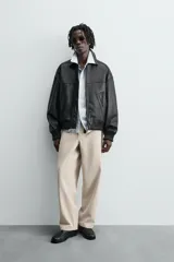 Pantalón chino color beige, de corte relaxed fit, confeccionado en tejido de mezcla de algodón y lino. Cuenta con bolsillos delanteros y traseros de vivo. Cierre frontal con cremallera y botón.