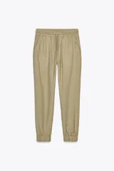 Pantalón jogger color arena de tiro alto con cintura elástica ajustable con cordones, bolsillos delanteros y puños elásticos en los tobillos.