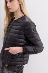 Campera corta negra de nylon rellena con pluma, corte holgado, cuello redondo y bolsillos con cierre.