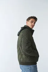 Campera de nylon color verde militar, con capucha, cierre frontal con cremallera, bolsillos laterales y frontales.