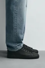 Zapatillas urbanas grises de caña baja, con cordones, puntera redondeada, forro interior en contraste y suela con ligera textura.