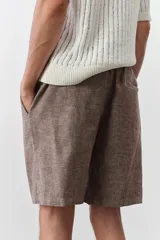 Short marrón claro en tejido liviano de lino y algodón. Modelo con elástico revestido y cordón para ajustar en la cintura, cierre con botón, bolsillos laterales y bolsillo insertado atrás.