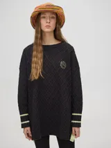 Sweater color crema con tejido en ochos, cuello redondo, puños acanalados con doble raya azul y tajos a los costados.