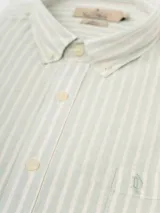 Camisa de manga larga a rayas verticales azules y blancas, con cuello abotonado y bolsillo en el pecho. Confeccionada en lino y algodón.