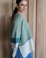 Buzo de punto con diseño de bloques de color negro, gris y beige. Tiene cuello redondo y mangas anchas tres cuartos.