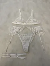 Conjunto de bralette de encaje color rosado con breteles regulables y tanga con corte medio, incluye portaligas con ligas.