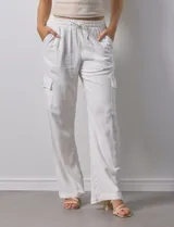 Pantalón cargo de lino color blanco, marca Marissa Olivia. Tiene pretina ancha elastizada con lazo de ajuste, bolsillos inclinados delanteros y bolsillos laterales con botón.