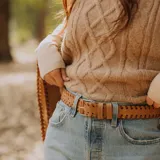 Cinto de cuero negro con trenzado artesanal, hebilla metálica plateada y doble pasador desmontable.