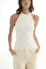 Blusa blanca sin mangas con lentejuelas alargadas y cuello halter.