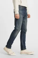Pantalón de jean azul oscuro, de corte skinny, con tiro medio y ajuste ceñido en muslos y piernas.