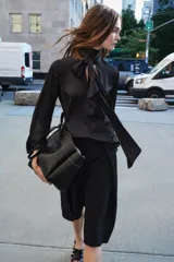 Blusa negra de cuello redondo con lazo en el mismo tejido. Manga larga acampanada y bajo recto.