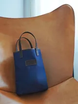 Bolso matero azul marino de lona con manijas de cuero marrón.