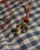 Collar con dije de bronce macizo con forma orgánica o de coral, suspendido de un hilo de seda natural color naranja.