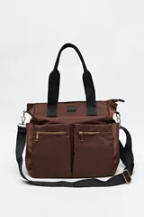 Bolso tote marrón de nylon con doble asa de mano negra y correa bandolera negra regulable y desmontable. Tiene dos bolsillos frontales con cierre metálico dorado.