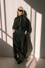 Campera negra de tela sintética con cierre frontal, cuello alto, mangas 3/4 con puños elásticos y cintura ajustable con cordón.