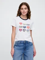 Remera blanca de algodón con cuello redondo en contraste azul marino y estampado frontal con el logo de Gap en forma de corazón en varios colores.