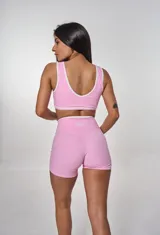 Conjunto deportivo rosa con top y short. El top es tipo corpiño con breteles y el logo 'bk.' estampado. El short es de tiro alto con cintura cruzada.