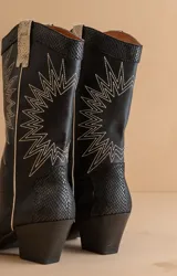 Botas de cuero sintético negro con bordado de estrellas blancas, caña media, puntera fina y tacón bajo.