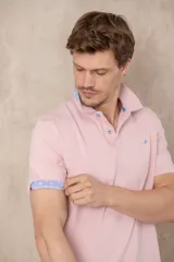 Chomba azul con cuello clásico, tapeta de dos botones y logo bordado en el pecho.