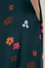 Vestido largo azul marino con estampado de flores en tonos naranja, rosa y celeste. Tiene corte holgado, mangas cortas y bolsillos laterales.