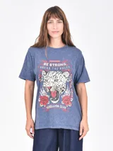 Remera azul con efecto acid wash, corte holgado y estampado frontal de un leopardo rugiendo rodeado de rosas y texto que dice "BE STRONG BREAK THE RULES" y "REBELLION CLUB".
