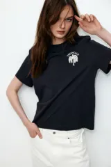 Remera negra de corte holgado en punto de algodón con cuello redondo y estampado de palmera con texto en el frente.