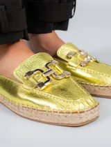 Sandalia alpargata color dorado, confeccionada en cuero metalizado, con base de yute y detalle de hebilla plateada.