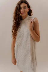 Vestido corto tejido color beige, sin mangas y con cuello redondo.