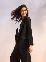 Blazer blanco de lino con doble botonadura y solapas de muesca. Tiene bolsillos delanteros con solapa y corte recto.