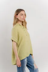 Blusa blanca de lino con escote en V abotonado y mangas cortas arremangadas.