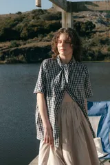Camisa de algodón a cuadros gingham azul y blanco con estampado de broderie blanco, lazo en el cuello, manga corta y corte oversize.