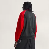 Campera Adidas Originals de corte holgado, con cuerpo en tejido de malla negro y mangas en color rojo con las icónicas tres tiras blancas. Presenta cierre frontal completo, cuello tipo bomber y logo del trébol bordado en el pecho.