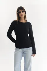 Sweater negro de punto con textura geométrica en relieve, cuello redondo y mangas largas.