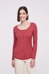 Remera de manga larga entallada en color blanco, confeccionada en algodón. Presenta cuello redondo con una hilera de botones frontales y un pequeño bolsillo en el pecho con detalle de botón.