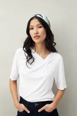 Remera de modal color marrón claro, de manga corta, con cuello asimétrico y detalle de nudo con frunces.