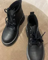 Borcego marrón de cuero con cordones, caña baja y suela track.