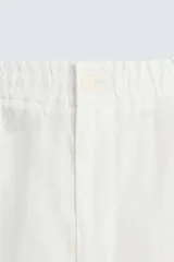 Pantalón blanco de lino con corte relajado (relaxed fit), cintura elástica, bolsillos frontales y un bolsillo trasero de vivo.