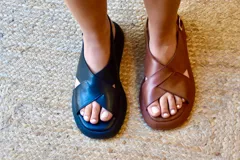 Sandalias negras de cuero con plataforma, tiras cruzadas y tobillera ajustable.