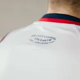 Camiseta de básquet Umbro del Club Nacional de Football. Diseño blanco con detalles en azul y rojo en cuello y sisas. Incluye logo de Umbro, escudo del club y sponsor Antel en el frente.