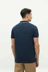 Remera polo verde militar con textura, corte regular, cuello clásico con detalles en azul marino y logo estampado en el pecho.