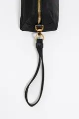 Neceser negro de nylon con correa desmontable, detalles en piel, logo metálico de Bimba y Lola, bolsillo interior y cierre con cremallera.