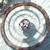 Anillo plateado de acero quirúrgico con diseño facetado.