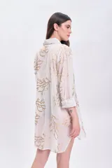 Camisa blanca de algodón con estampado de ramas doradas, de corte recto y mangas largas.