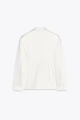 Blazer blanca de tejido satinado, con cuello solapa y escote pico, manga larga con hombreras, bolsillos con solapa en delantero y falso bolsillo en pecho, bajo con abertura en espalda y cierre frontal con botón.