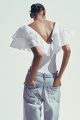 Body blanco con escote en pico y tirantes anchos con volantes.
