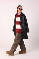 Trench negro de cuero ecológico con cuello clásico, cierre abotonado y bolsillos laterales.