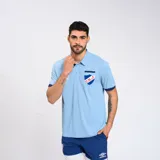 Remera polo celeste con detalles en azul marino en cuello y mangas. Escudo del Club Nacional de Football bordado en el pecho y logo de Umbro estampado en blanco.