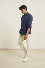 Camisa azul marino de lino y algodón, con cuello abotonado, manga larga con puños enrollados, bolsillo de parche en el pecho y cierre frontal con botones.