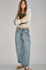 Jean de denim rígido azul claro, tiro medio-alto, con calce holgado y piernas anchas que se estrechan ligeramente hacia el tobillo. Presenta pinzas en la zona de las rodillas y un recorte en el lateral.